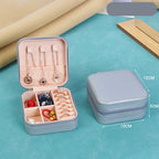 Jewelry organizer with jewelry items on a blue surface, showing dimensions.