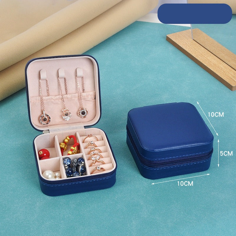 Blue jewelry case with open lid showing earrings and other accessories on a blue surface.