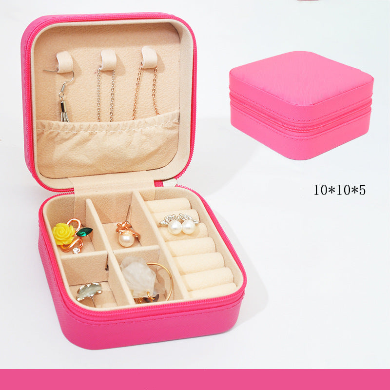Pink jewelry box with compartments containing earrings and a necklace, on a white background.