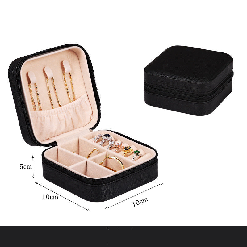 Black jewelry box with jewelry inside, open to show compartments, on a white background.
