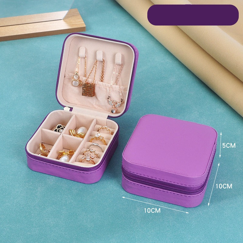 Purple jewelry case with jewelry items on a blue surface, showing dimensions.