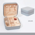 Gray jewelry box with open lid showing earrings, closed on a white background