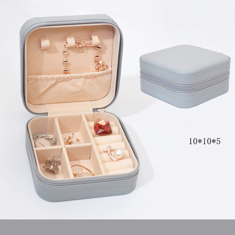 Gray jewelry box with open lid showing earrings, closed on a white background
