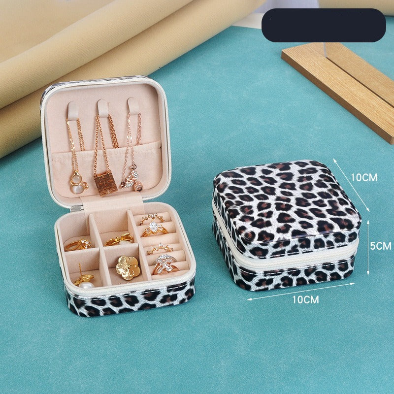 Leopard print jewelry case with open lid displaying jewelry on a blue surface