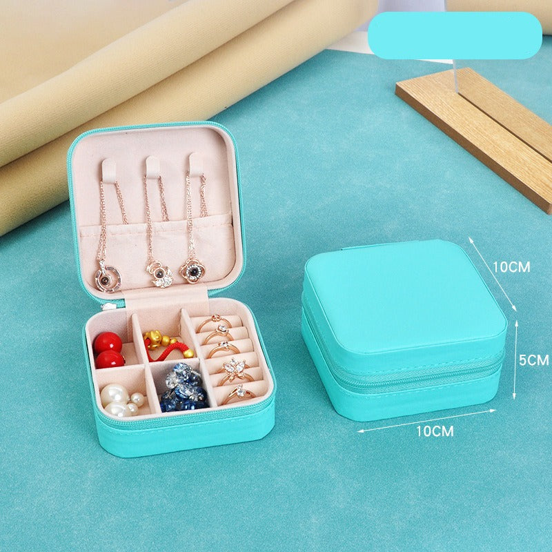 Teal jewelry box with open lid showing necklaces and jewelry, on a blue surface with measurements.